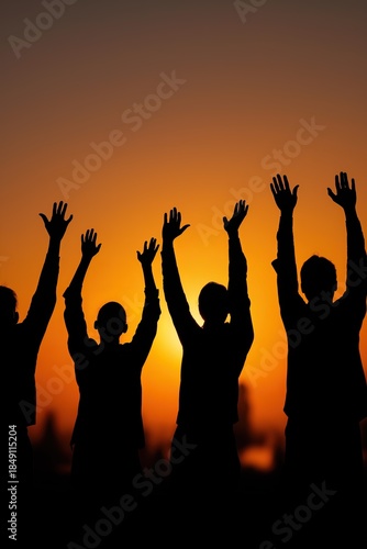 Silhouetted group celebrating at sunset with raised hands