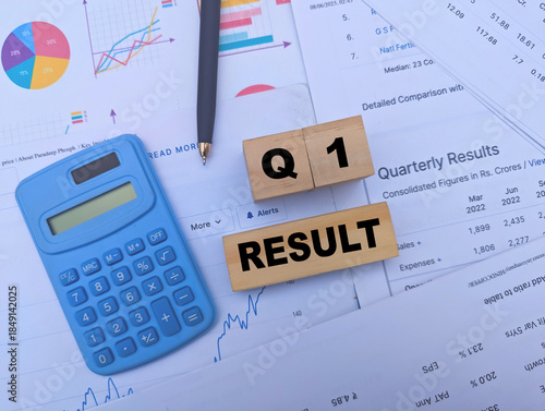 Q1 Result text on wooden blocks with blue calculator and financial charts for business analysis