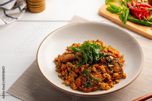 Stir Fried Crispy Basil with Pork and Black Preserved Egg in white plate (Kai Yiew Ma Kra Prao Krob)