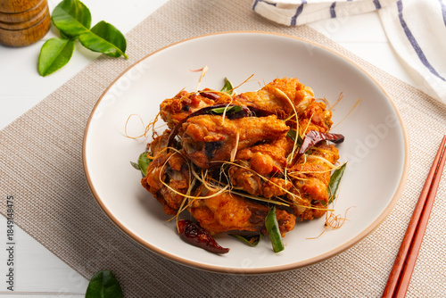 Fried chicken wingstick with fish sauce.Chicken drumettes with crispy lemongrass ,chilli and Kaffir lime leaves in white plate.