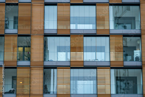 Modern residential building facade with glazed loggias and vertical wooden louvers creating a rhythmic contemporary architectural pattern