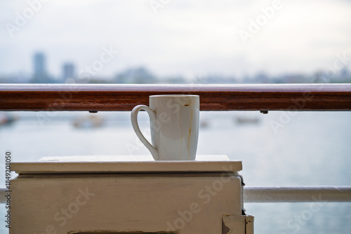 Morning coffee gone rogue  left dirty and lonely on the ship's metal box by the railing.