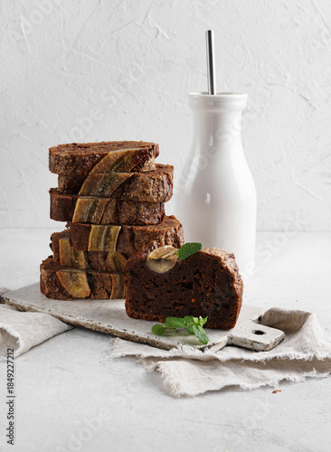 A Piece of chocolate banana bread with bottle of milk nearby. Stack of pieces of bread. Breakfast concept. Selective focus.