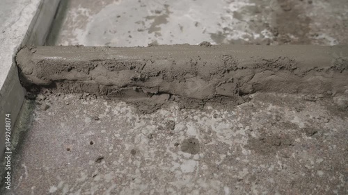 Close-up of wet cement mortar drying and hardening on a concrete surface. The texture of the fresh building material during construction