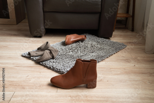 Brown leather ankle boot on floor near rug in home interior