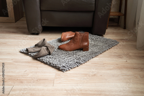 Pair of brown leather ankle boots on rug in cozy living room