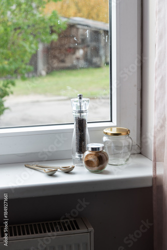 Spices and pepper mill on a windowsill