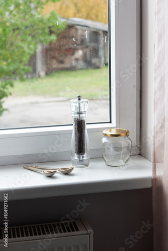 Empty spice jars and pepper mill on a windowsill