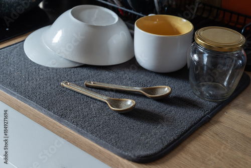 Clean washed dishes arranged on a gray drying mat on a kitchen countertop