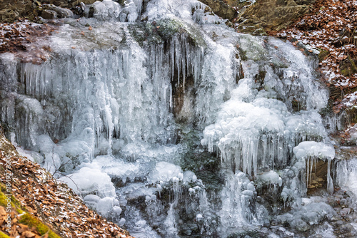 Wallpaper Mural A frozen waterfall cascading down the rocky terrain with intricate icicles forming in winter's embrace, creating a stunning display of nature's artistry. Pure winter magic! Torontodigital.ca