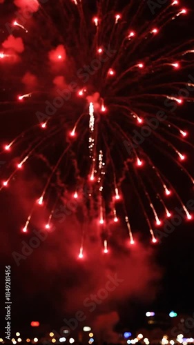 Fiery red fireworks display against dark sky celebratory backdrop with illuminating trails and bursts