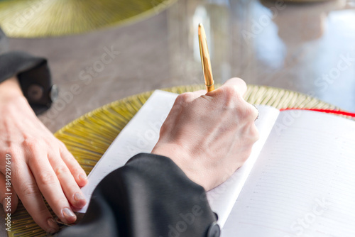 Close-up of a hands holding a pen and a notebook.