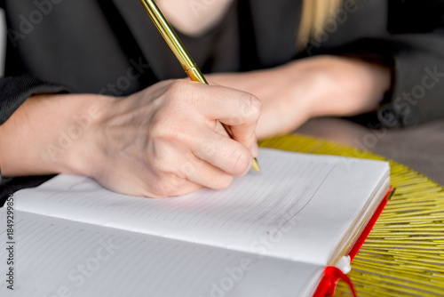 Close-up of a hands holding a pen and a notebook.