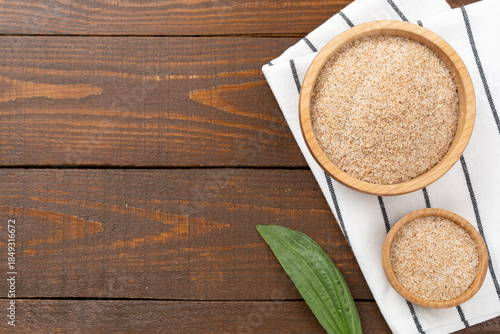 Φωτογραφία Psyllium husk powder with fresh leaves on wooden background, top view