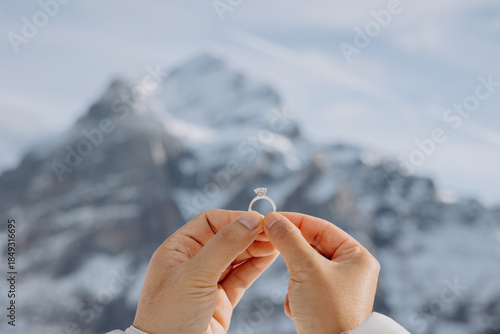 Young woman holding out her hand with an engagement ring against a mountain landscape background