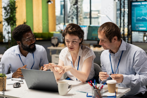 Foto African American and Caucasian colleagues sitting together in modern office, reviewing financial charts on laptop
