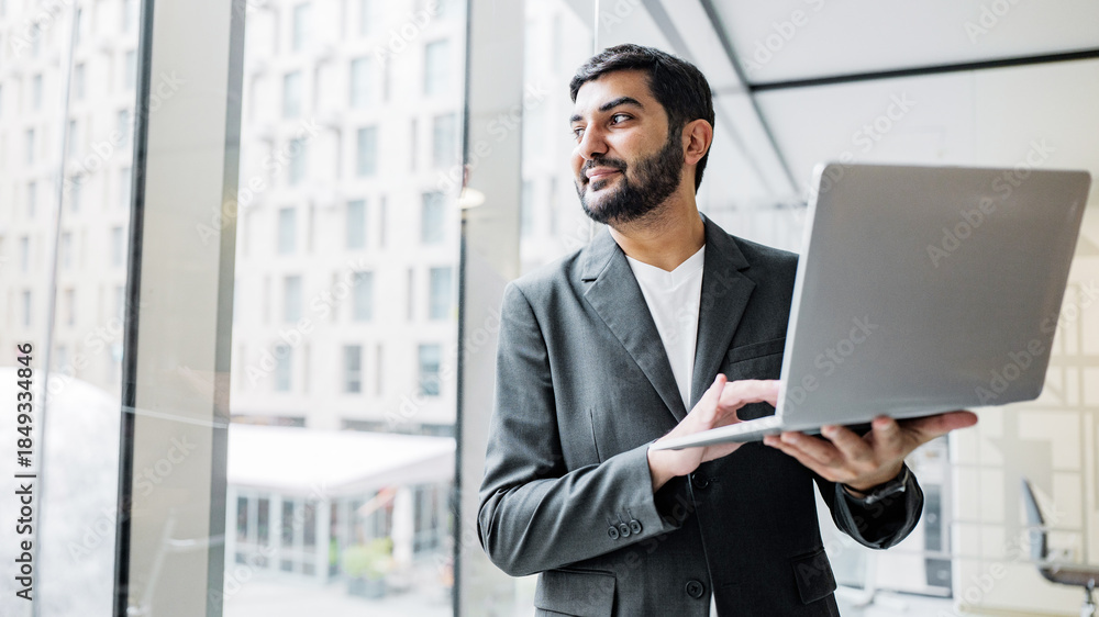 Fototapeta premium Businessman working with laptop in office setting