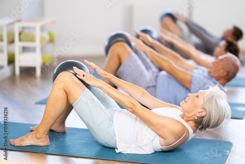 Foto People of different ages doing pilates exercises with fitness ball during group