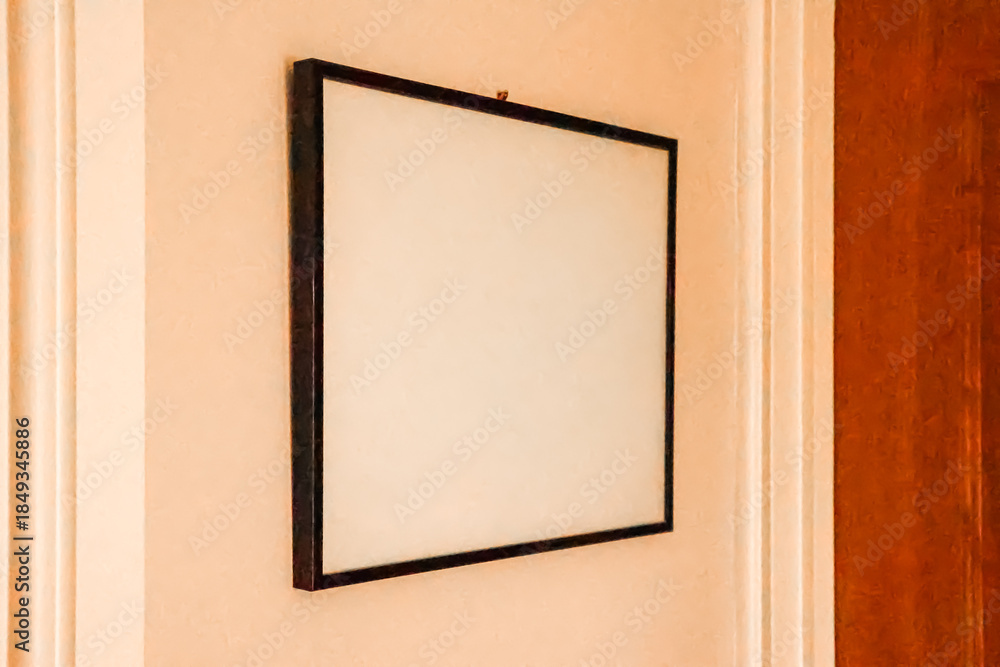 Fototapeta premium Blank white square frame hangs on a peach colored wall, offering copy space for art, advertising, and home decoration