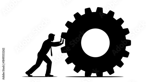 A man in a suit pushes a large gear with both hands in an industrial environment from a side viewpoint.