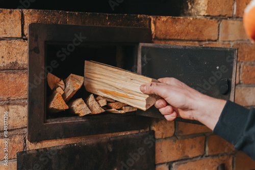  Loading Firewood Into a Stove.Heating with the stove. Heating a house with wood. Hand Placing Firewood in Brick Oven.Person Holding Stack of Firewood. 