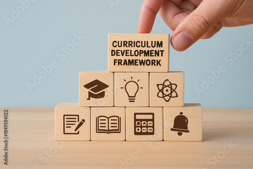 Curriculum Development Framework A human hand arranges wooden cubes with subject icons, illustrating the systematic methodology for structuring educational content and strategic planning