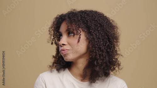 Young Woman Reacting with Doubt and Disapproval on beige Background. She frowns, hesitates, looks unconvinced