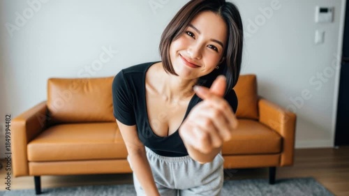 カメラに向かって指ハートのポーズをする笑顔のチャーミングな女性