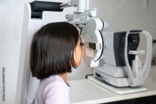 Fotografía A happy 6-year-old girl undergoes a vision test using a phoropter during a pediatric eye exam at an ophthalmology clinic