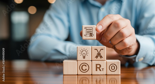 Intellectual Property Protection A human hand places wooden cubes with patent icons, showing the systematic methodology for securing legal rights over scientific discoveries and problem-solving