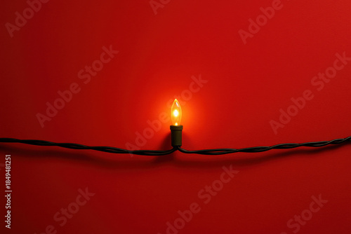Minimal Christmas decoration scene, single glowing string light on smooth red backdrop with subtle shadows, modern festive style, warm cozy mood, simple composition, copy space for seasonal design