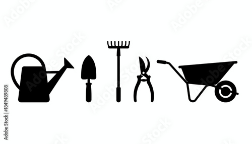 Gardening tools lie on the ground near a wheelbarrow in a serene outdoor setting with a watering can.