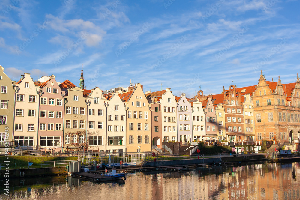 Naklejka premium The waterfront in Gdansk, Poland. Buildings and the river under bright skies. Green Gate in the background