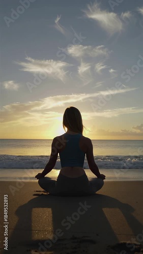Silhouette of a person meditating on the beach at sunset, embracing peace and tranquility, vertical shot
