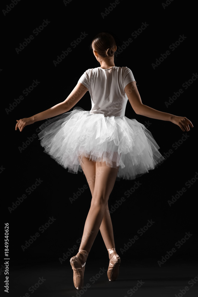 Fototapeta premium Young ballerina on dark background, back view