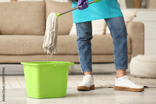 Young woman with mop and bu...
