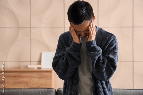 Sad young Asian man at home