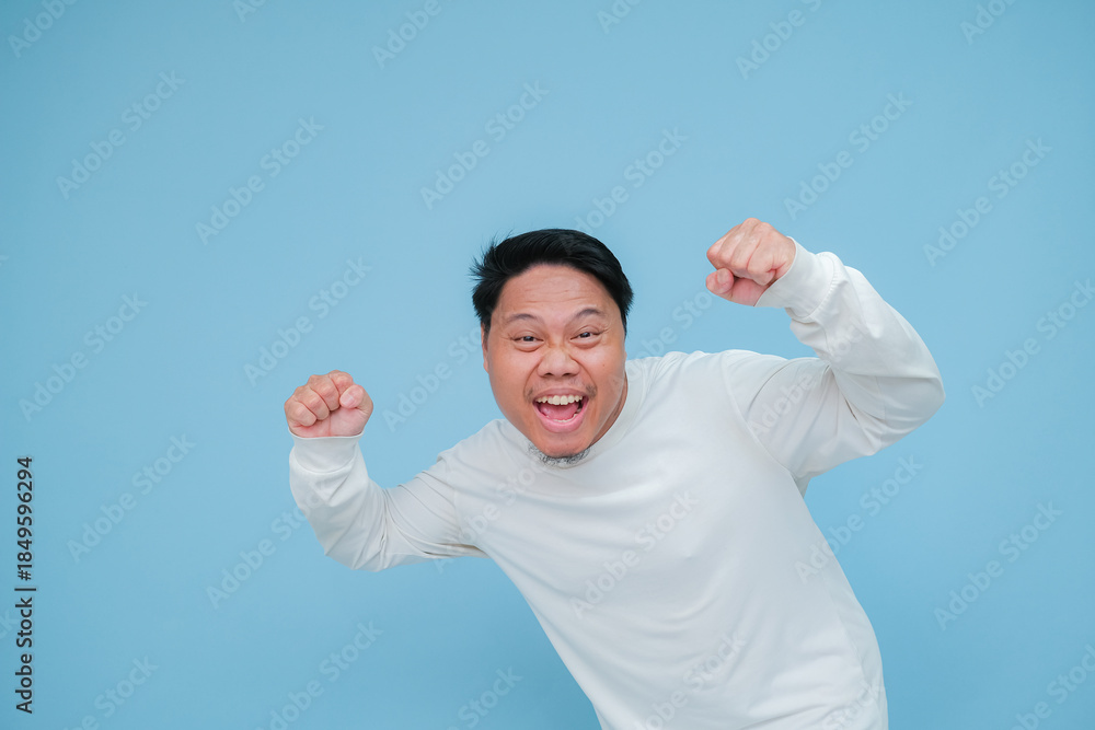 Fototapeta premium A young Asian man is expressing his happiness over his success while wearing white t-shirt
