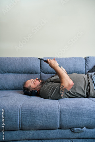 Man using device while lying on couch
