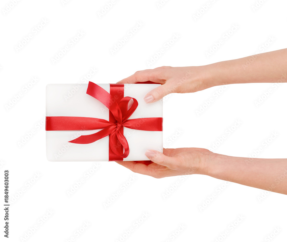 Fototapeta premium Female hand holding or present white gift box with red silk bow isolated on white background with clipping path. Design element.