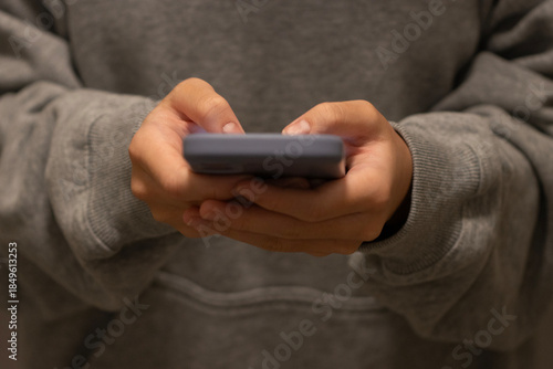 Closeup of a teenager using a mobile phone. Social media apps, screen time, short video streaming, and video games concepts.