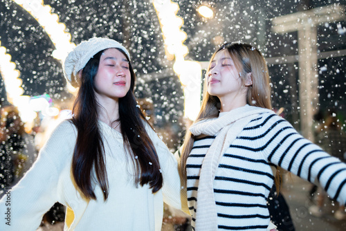  A young woman wearing a scarf and gloves is smiling outdoors in the snow during the winter.