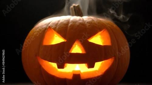 Jack-o'-lantern with glowing carved face, smoke rising, creating a spooky atmosphere