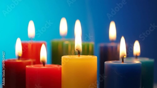 Lit colorful pillar candles casting warm glows against a serene blue background