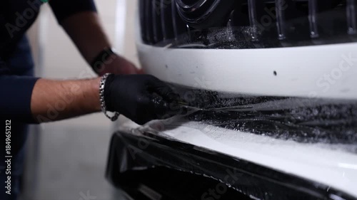 Car detailing. A technician cuts away protective film with a knife.