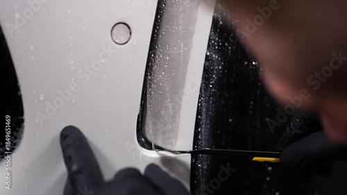 A technician removes protective film from a car. Auto detailing.