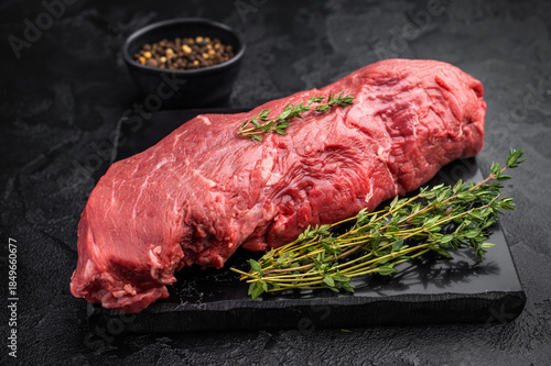 Schilderij op canvas Raw beef tenderloin on dark background with herbs and spices