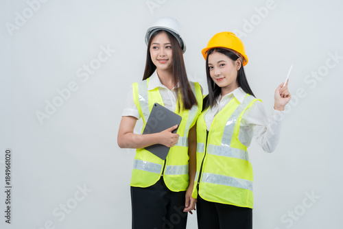 Asian female engineers collaborate on digital construction data, representing smart project coordination, technology-driven industry, women empowerment, and modern safety standards.