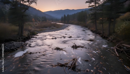 A tranquil riverside scene featuring gently flowing water along the shore, with fallen autumn leaves and soft foam resting at the edge.