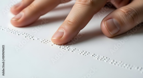 A close-up of braille text on a page with fingertips touching.